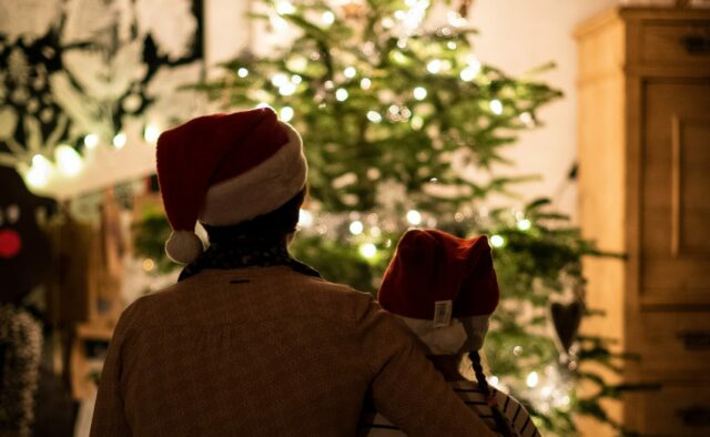 2 people sat in front of a christmas tree