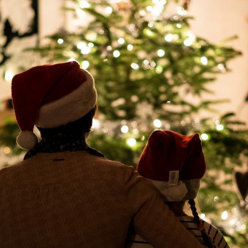 2 people sat in front of a christmas tree